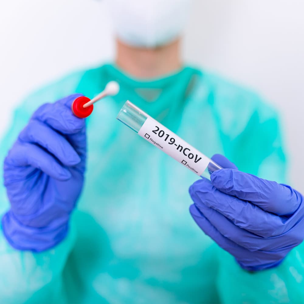 Operatore sanitario con DPI mostra un tampone nasofaringeo e la provetta per il test antigenico rapido SARS-CoV-2